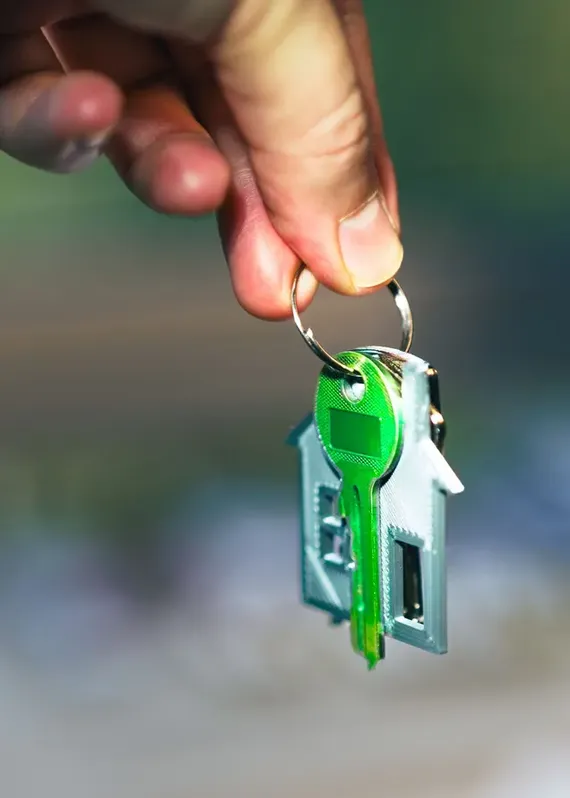 Main tenant un trousseau de clés avec un porte-clés en forme de maison