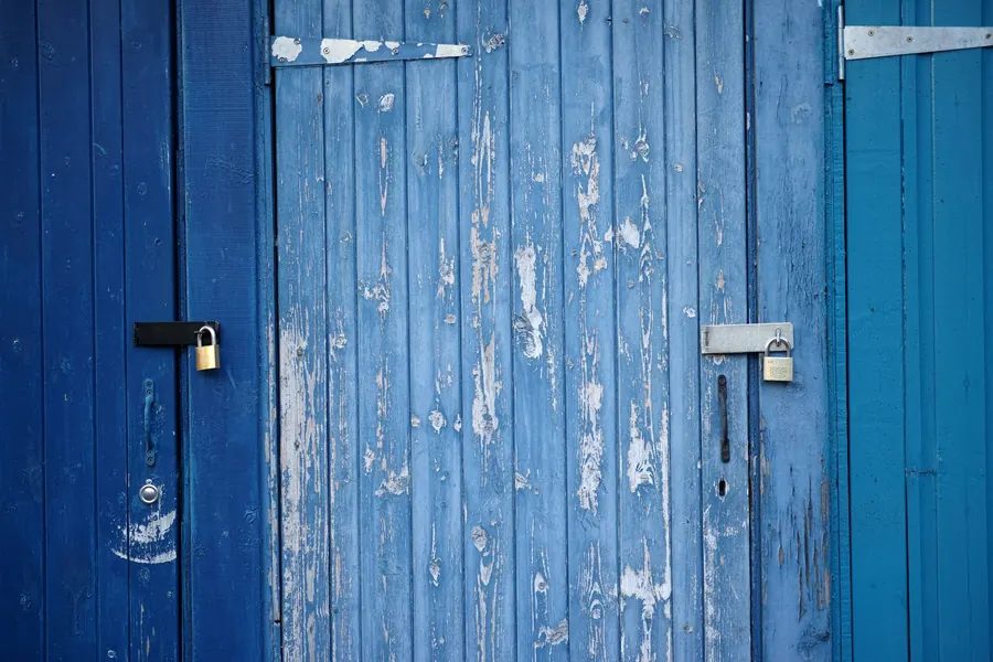 Porte de cabanon en bois bleu fermée par deux cadenas